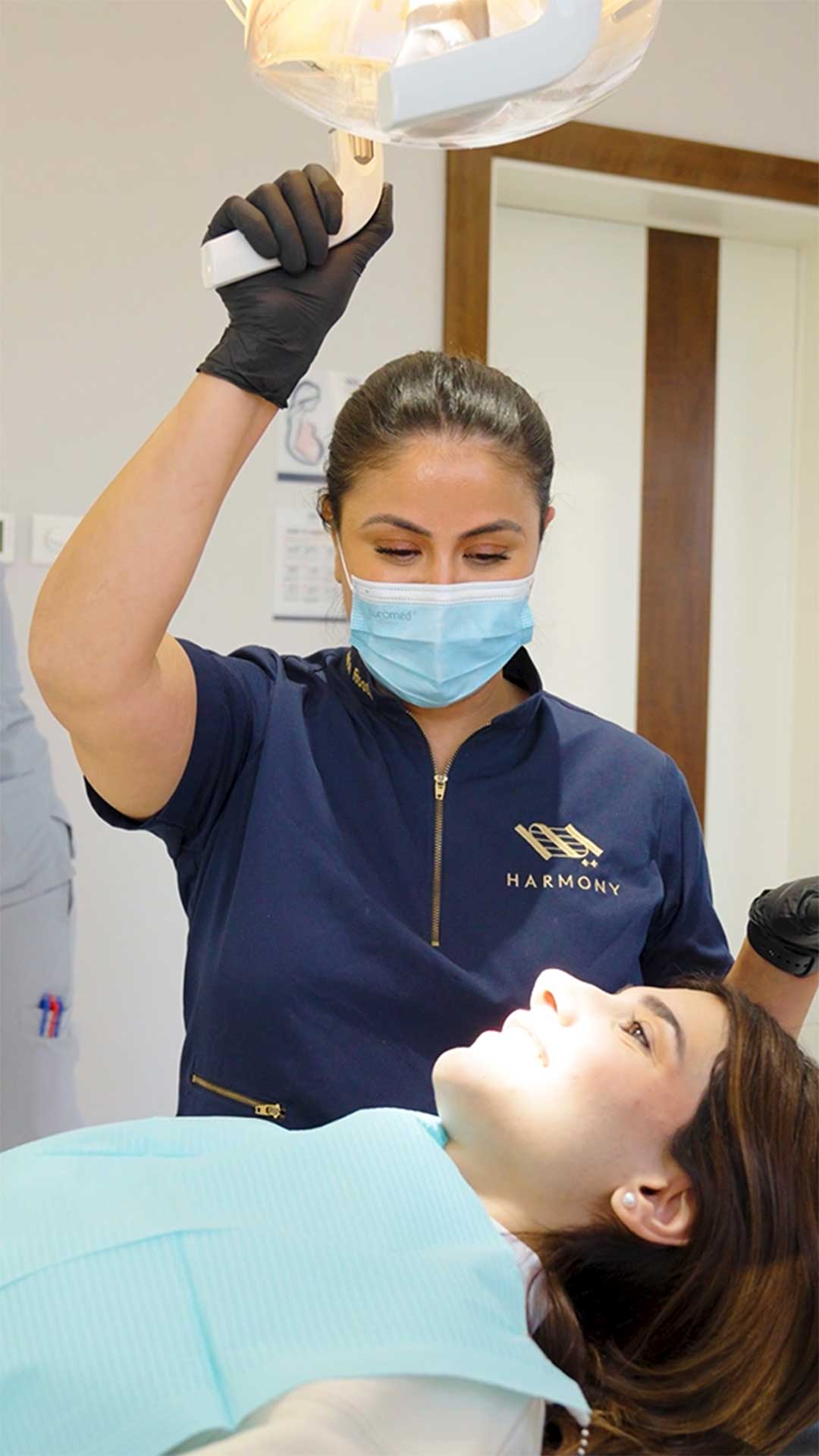 Female dental hygienist at Harmony Medical Center performing a routine dental cleaning