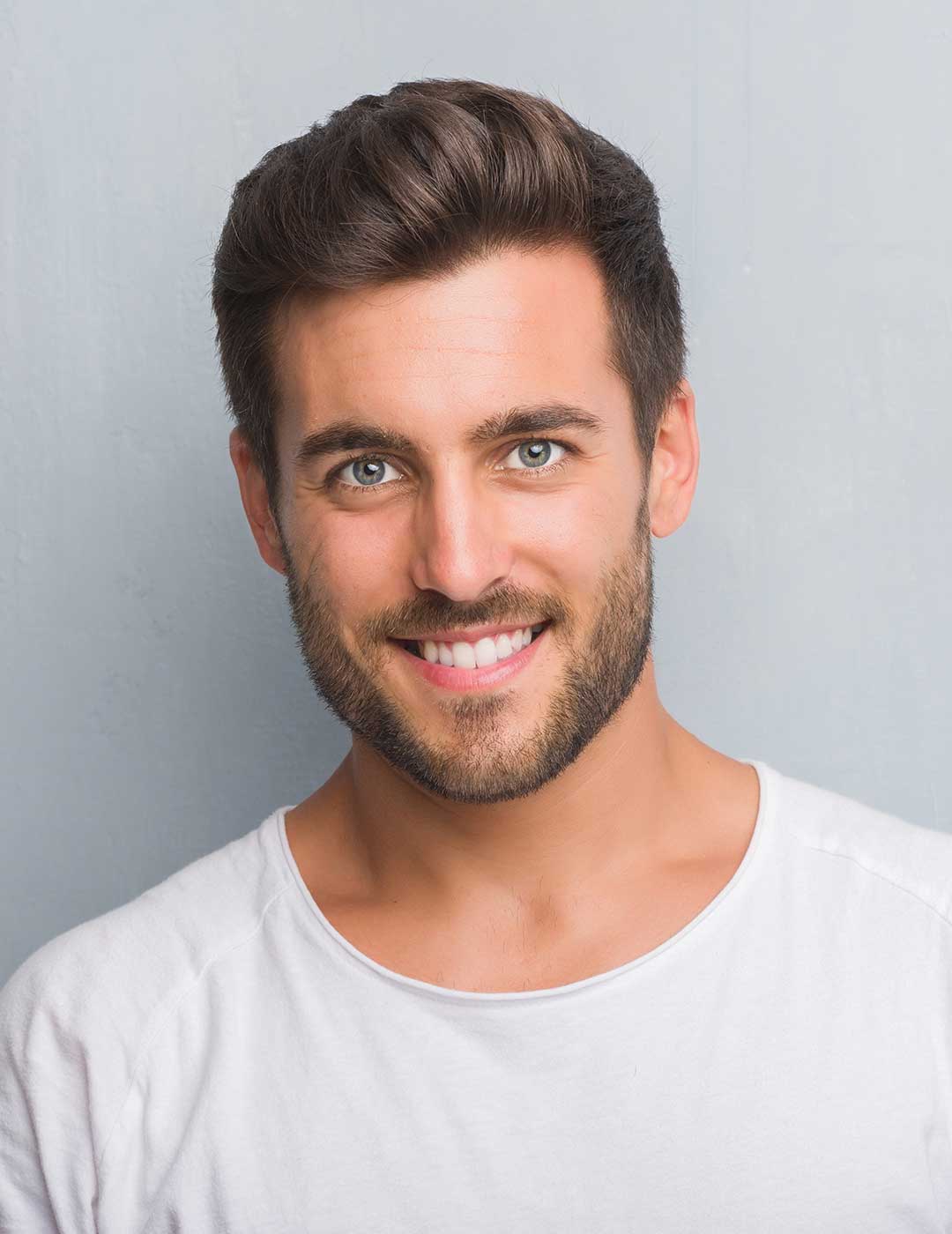 Handsome man smiling confidently, showcasing a natural-looking smile after receiving inlays and onlays dental treatment.